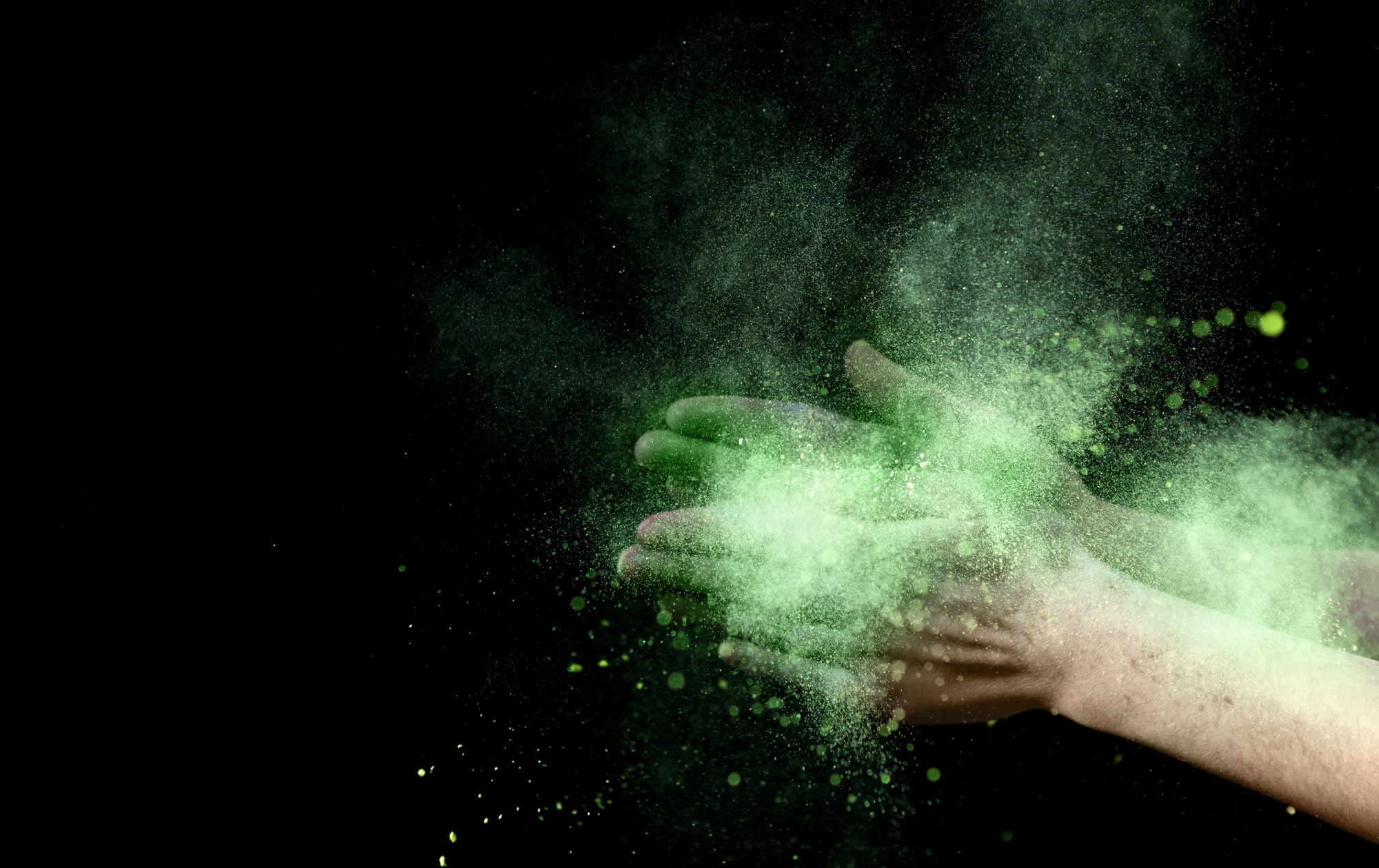 Yellow explosion of holi color powder inside clapping hands